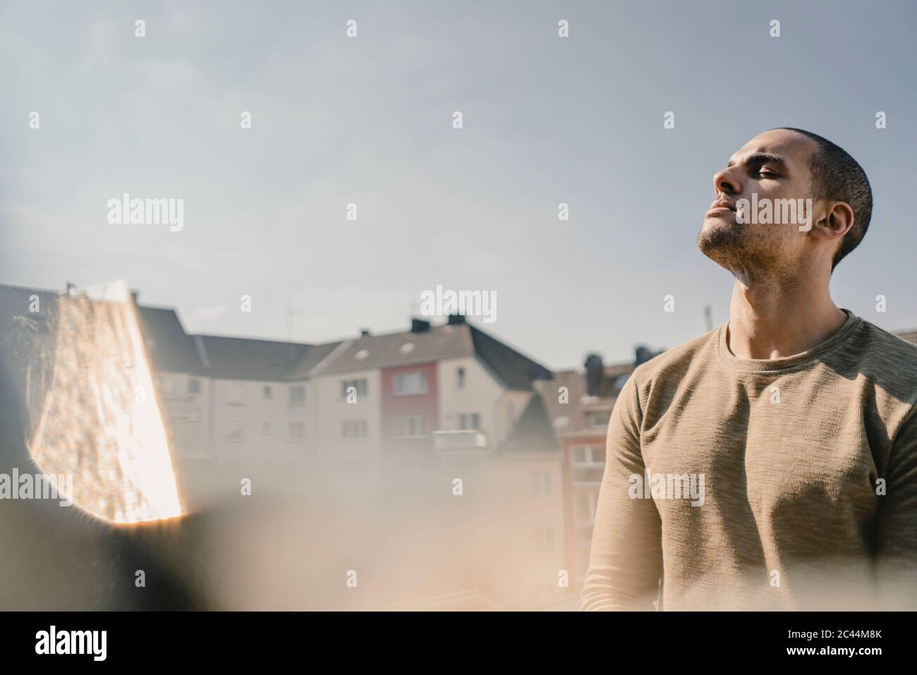 Young man standing on balcony, relaxing Stock Photo