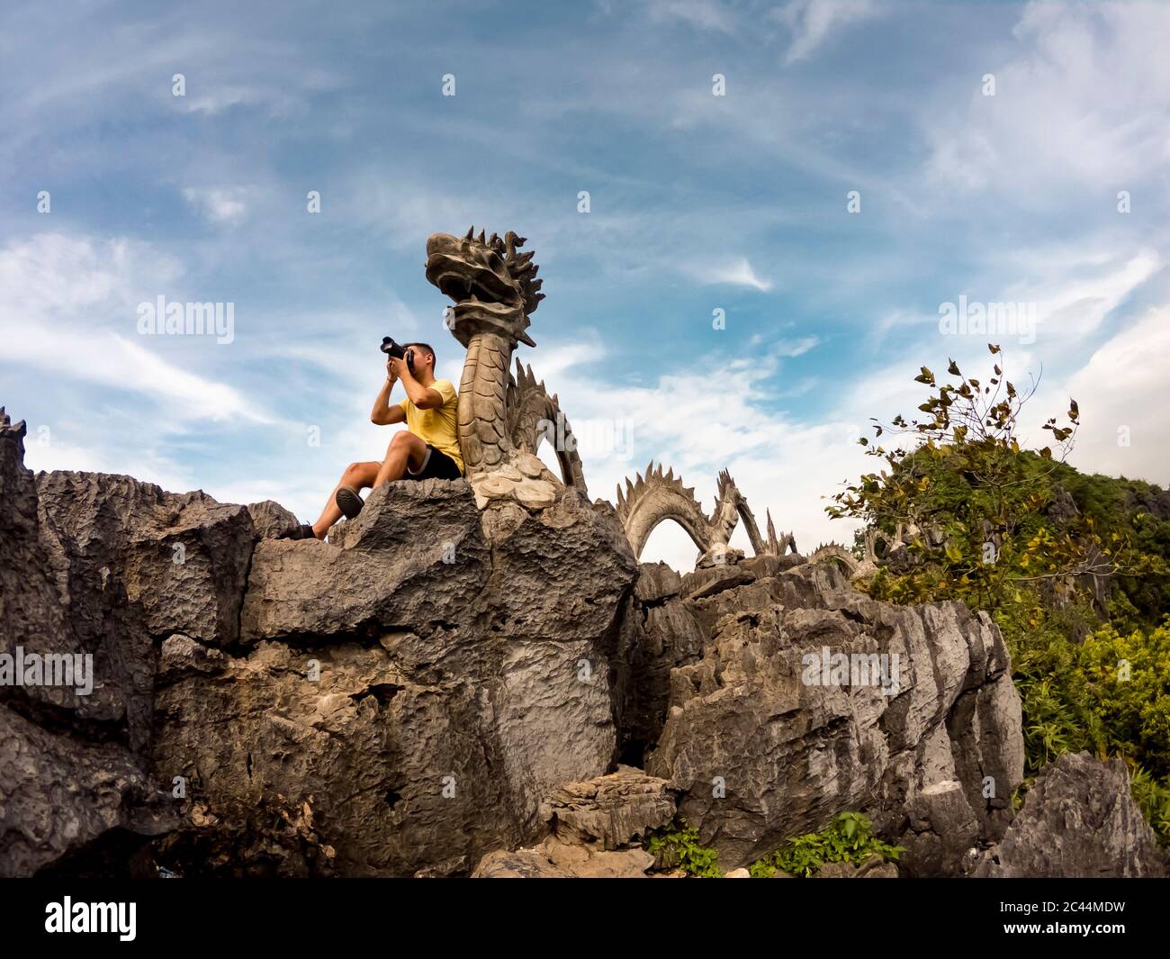 Vietnam, Ninh Binh Province, Ninh Binh, Male tourist taking photos in front of dragon sculpture Stock Photo