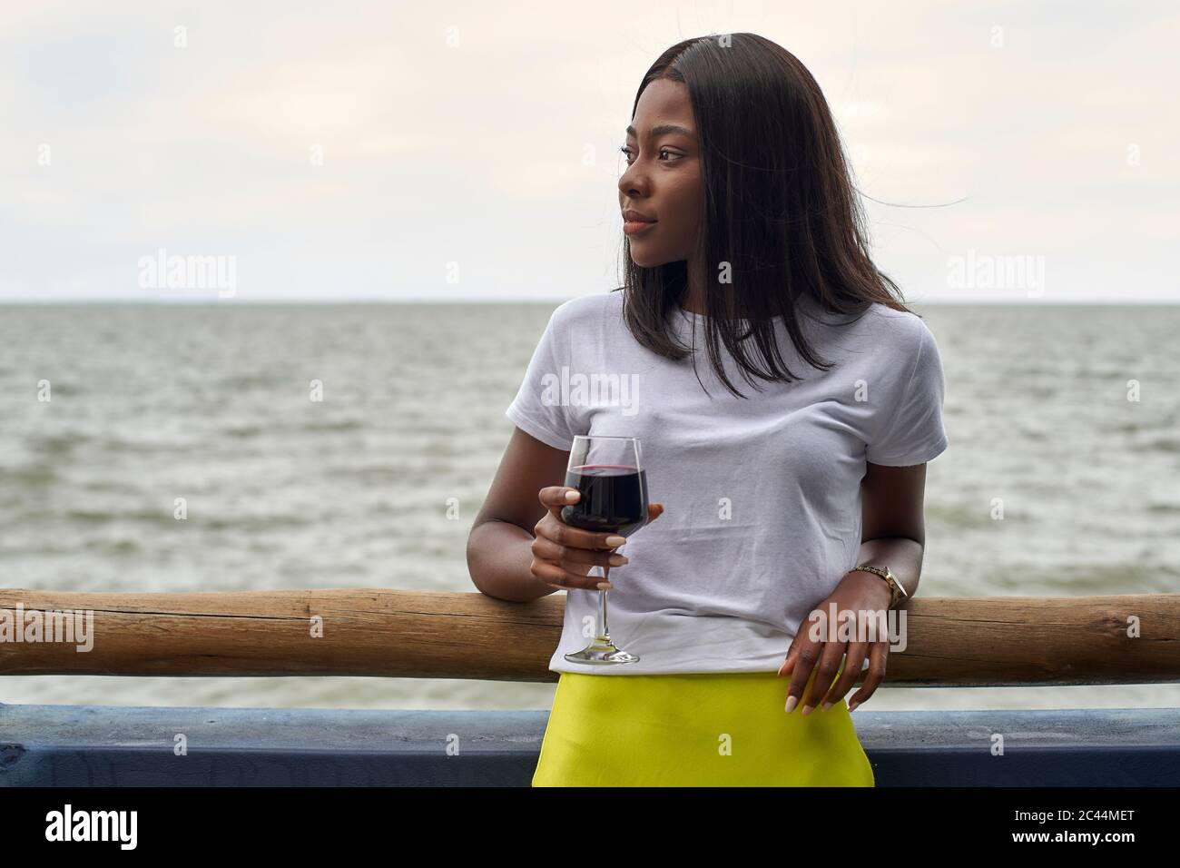Portrait of young woman with glass of red wine in front of the sea Stock Photo