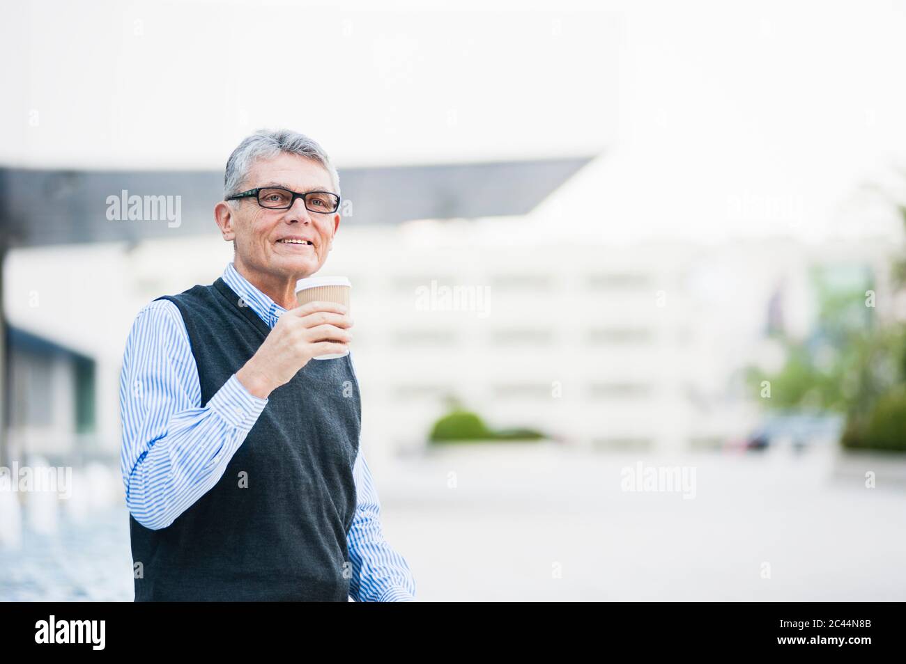 Portrait of senior businessman with coffee to go outdoors Stock Photo