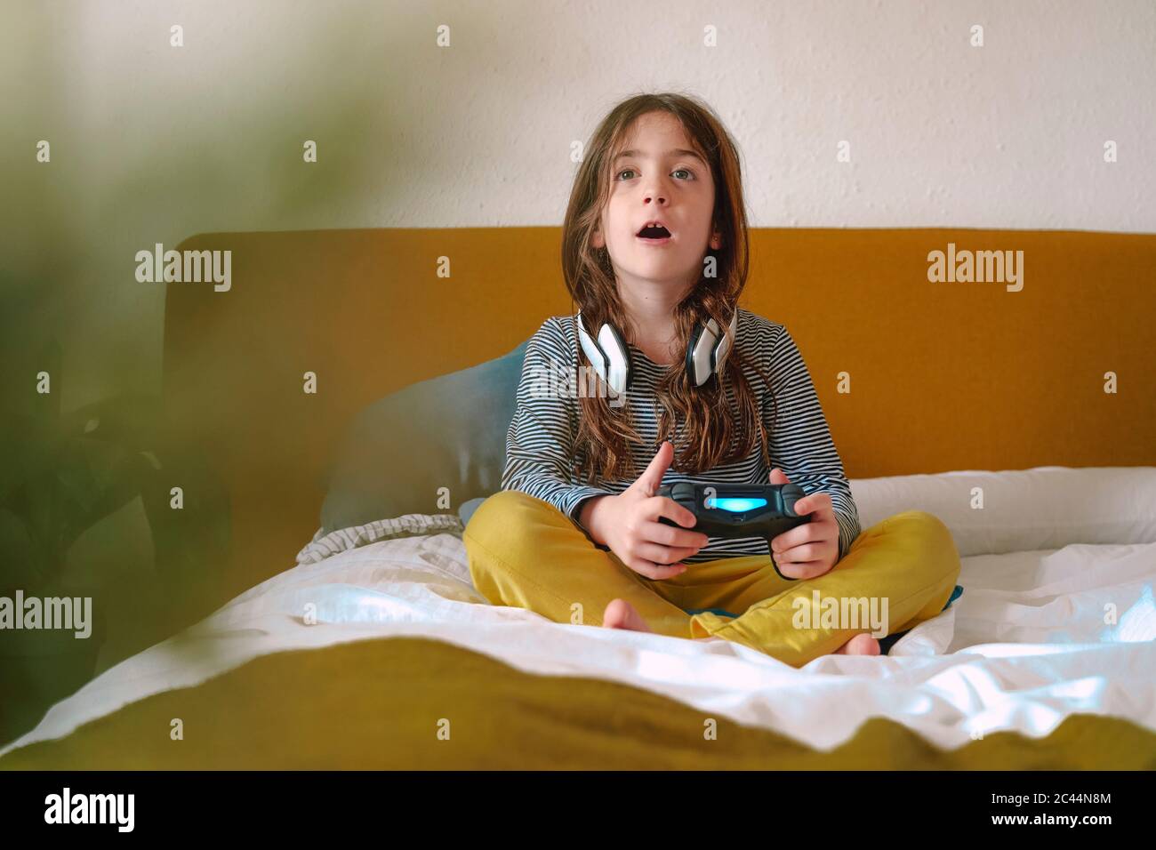 Girl playing video game sitting on bed Stock Photo Alamy