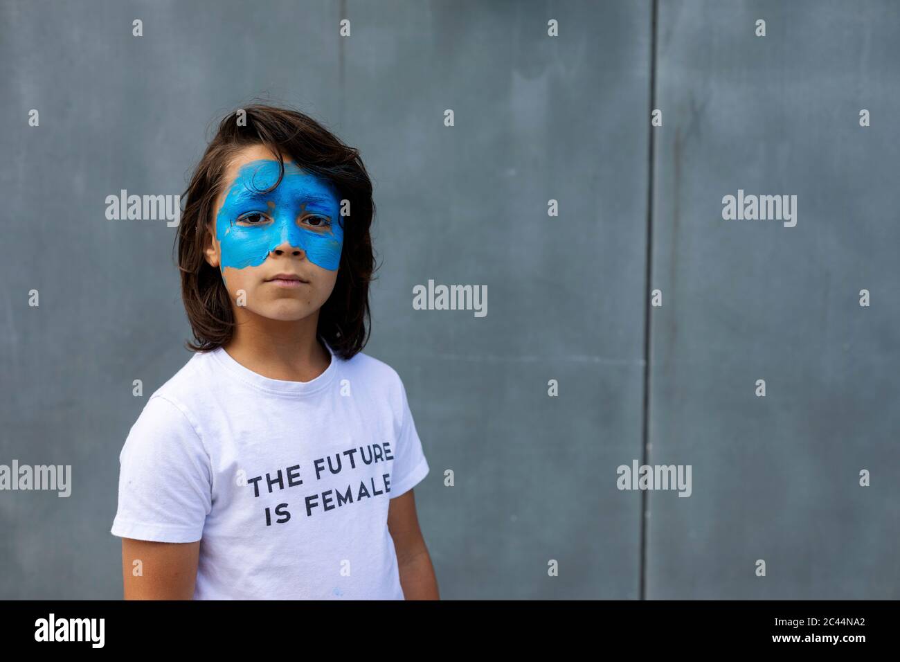 Portrait of boy with painted blue mask on his face wearing t-shirt with imprint 'The Future is Female' Stock Photo