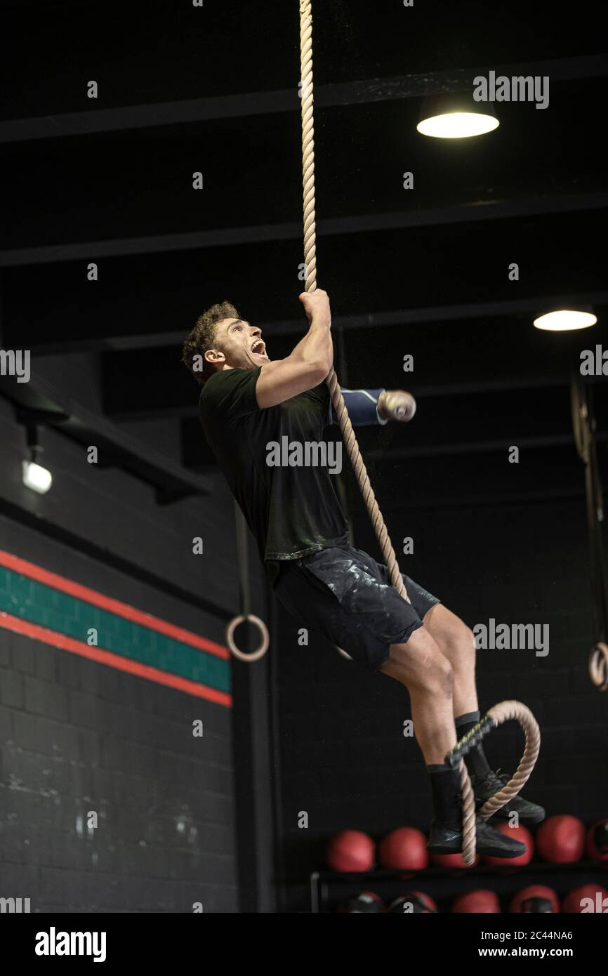 Athlete with an amputated arm climbing rope Stock Photo