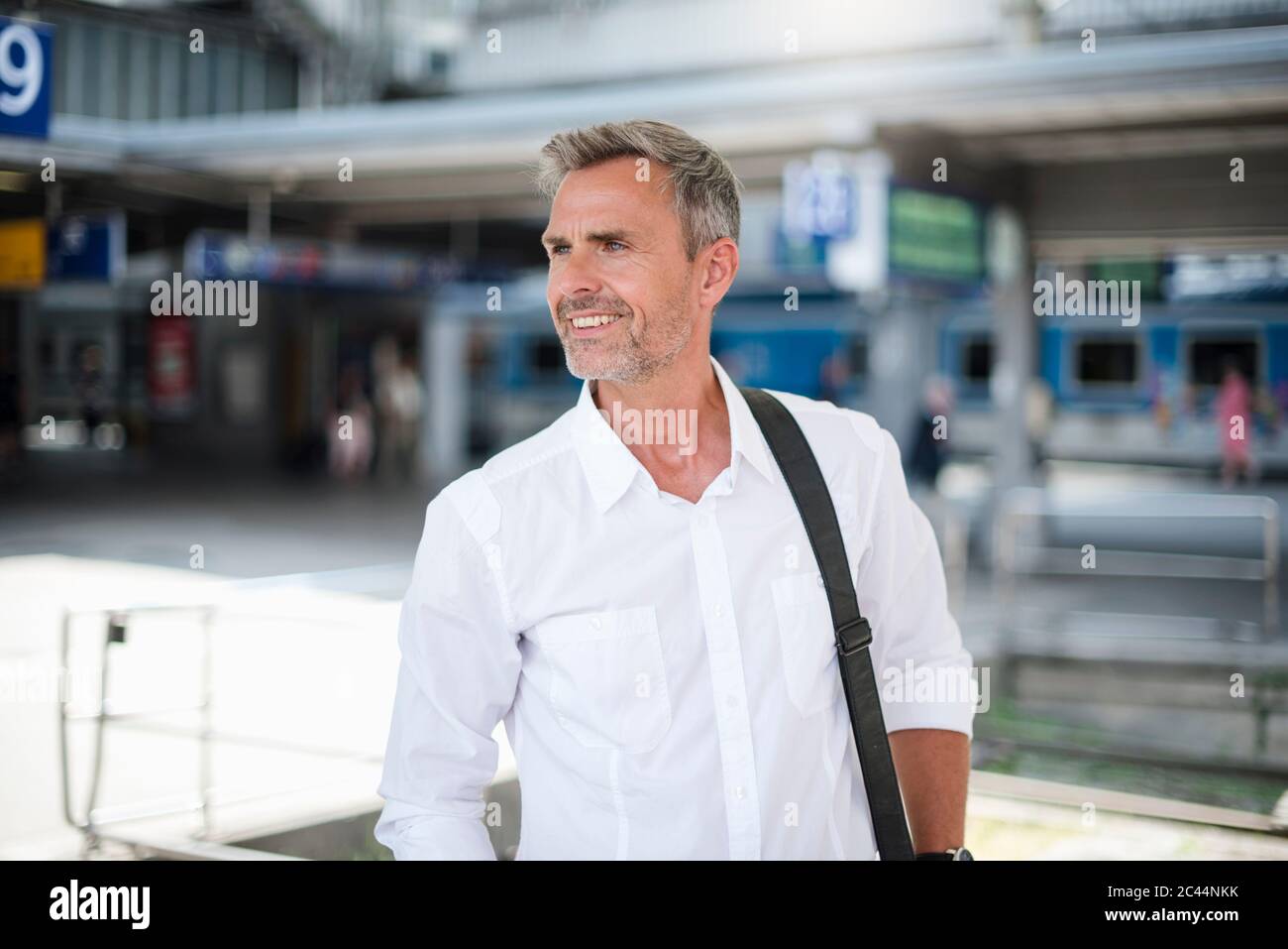 Smiling businessman looking away while standing at railroad station Stock Photo