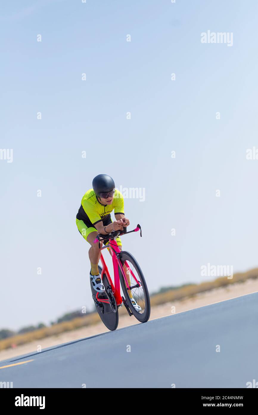 Determined cyclist riding bicycle on road against clear blue sky hi-res ...