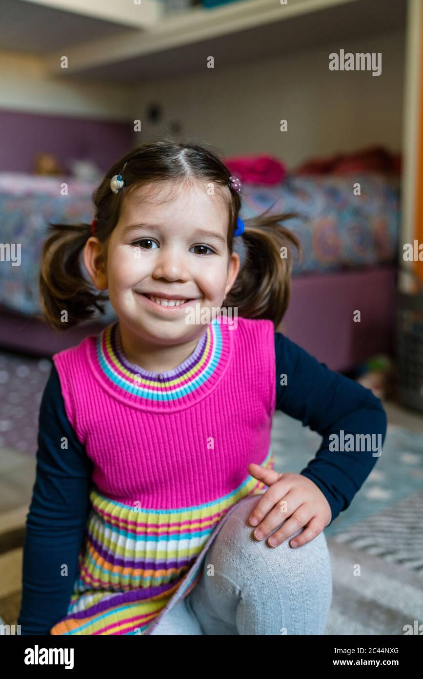 Portrait of smiling cute girl sitting in bedroom at home Stock Photo ...