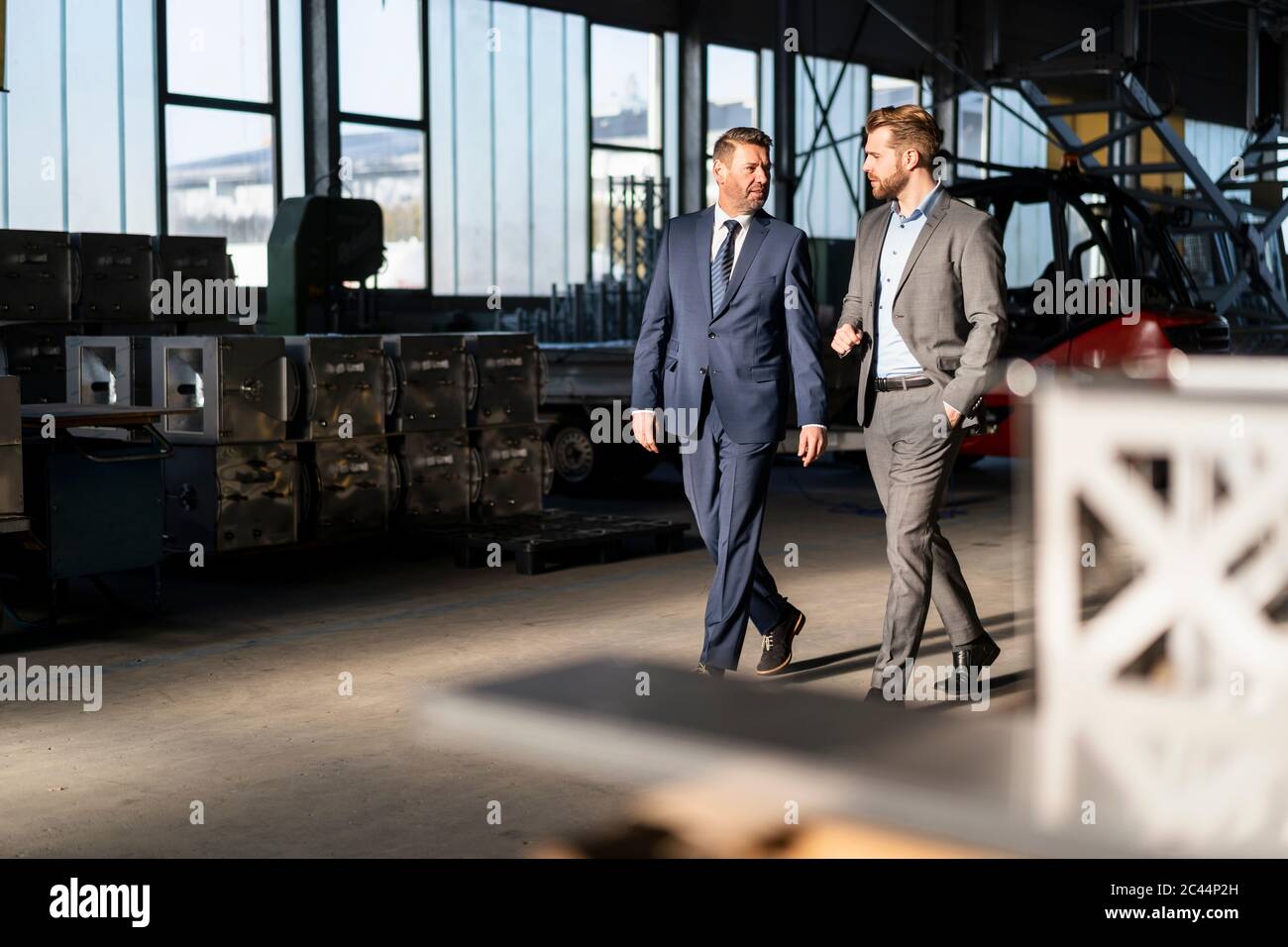 Two businessmen walking and talking in a factory Stock Photo - Alamy