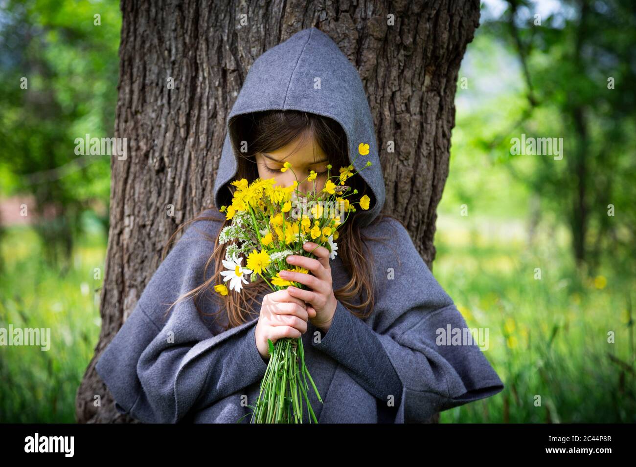 Girl smelling on bunch of yellow wildflowers Stock Photo