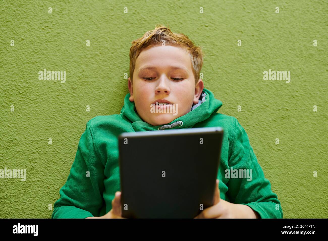 Boy using digital tablet on green carpet at home Stock Photo