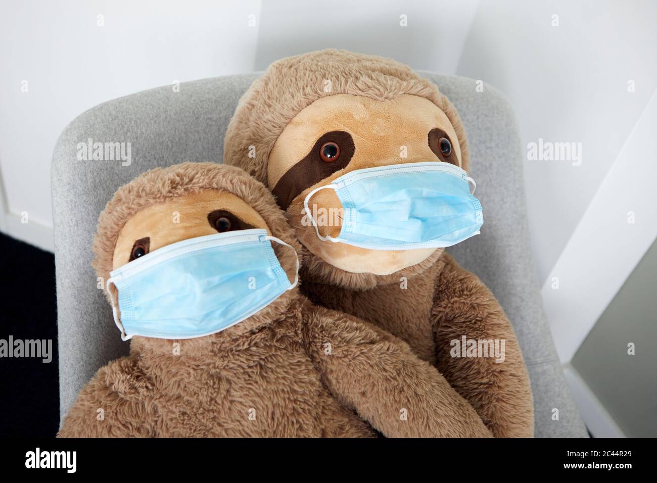 Two soft toys on arm chair with protective masks Stock Photo