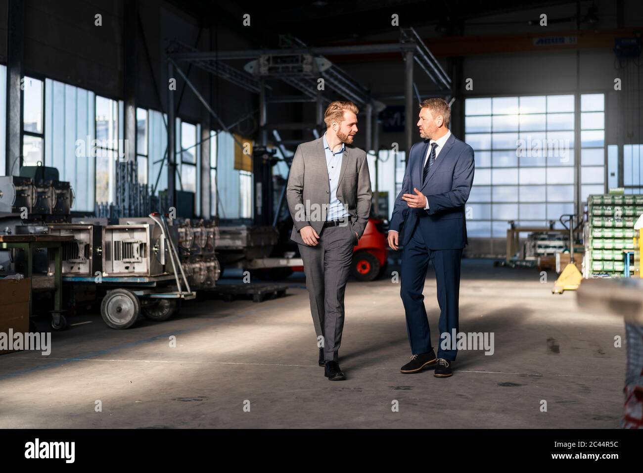 Two businessmen walking and talking in a factory Stock Photo - Alamy