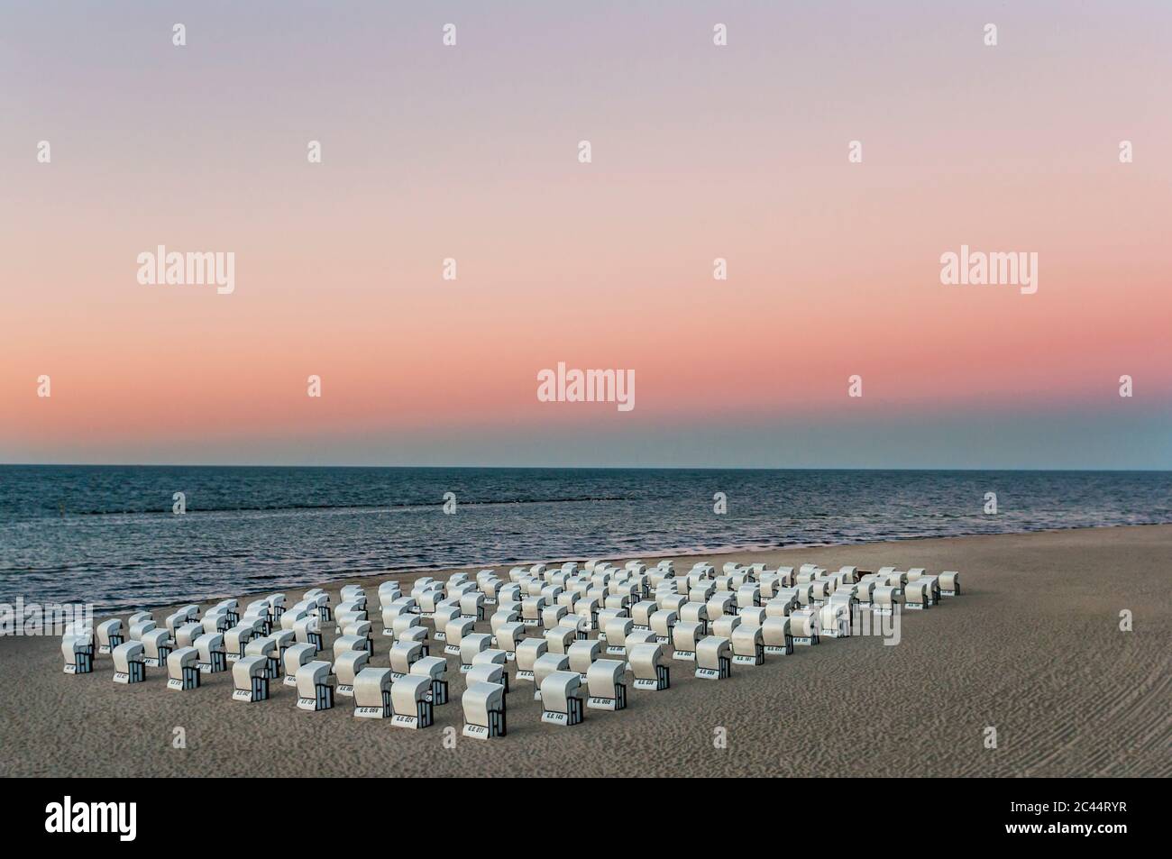 Hooded chairs at beach against sky during sunset, Ruegen, Germany Stock Photo