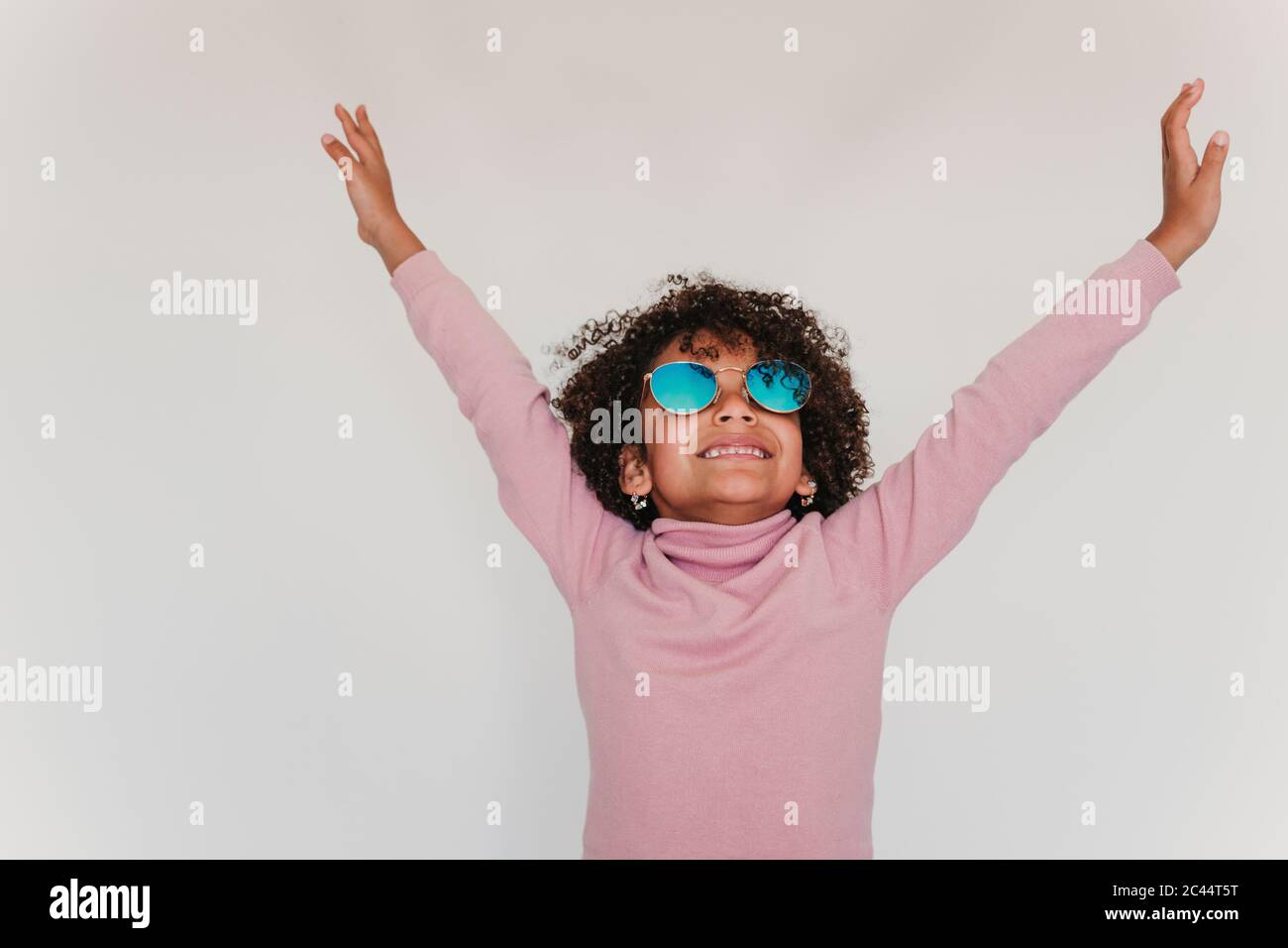 Portrait of happy little girl wearing pink turtleneck pullover and mirrored sunglasses Stock Photo