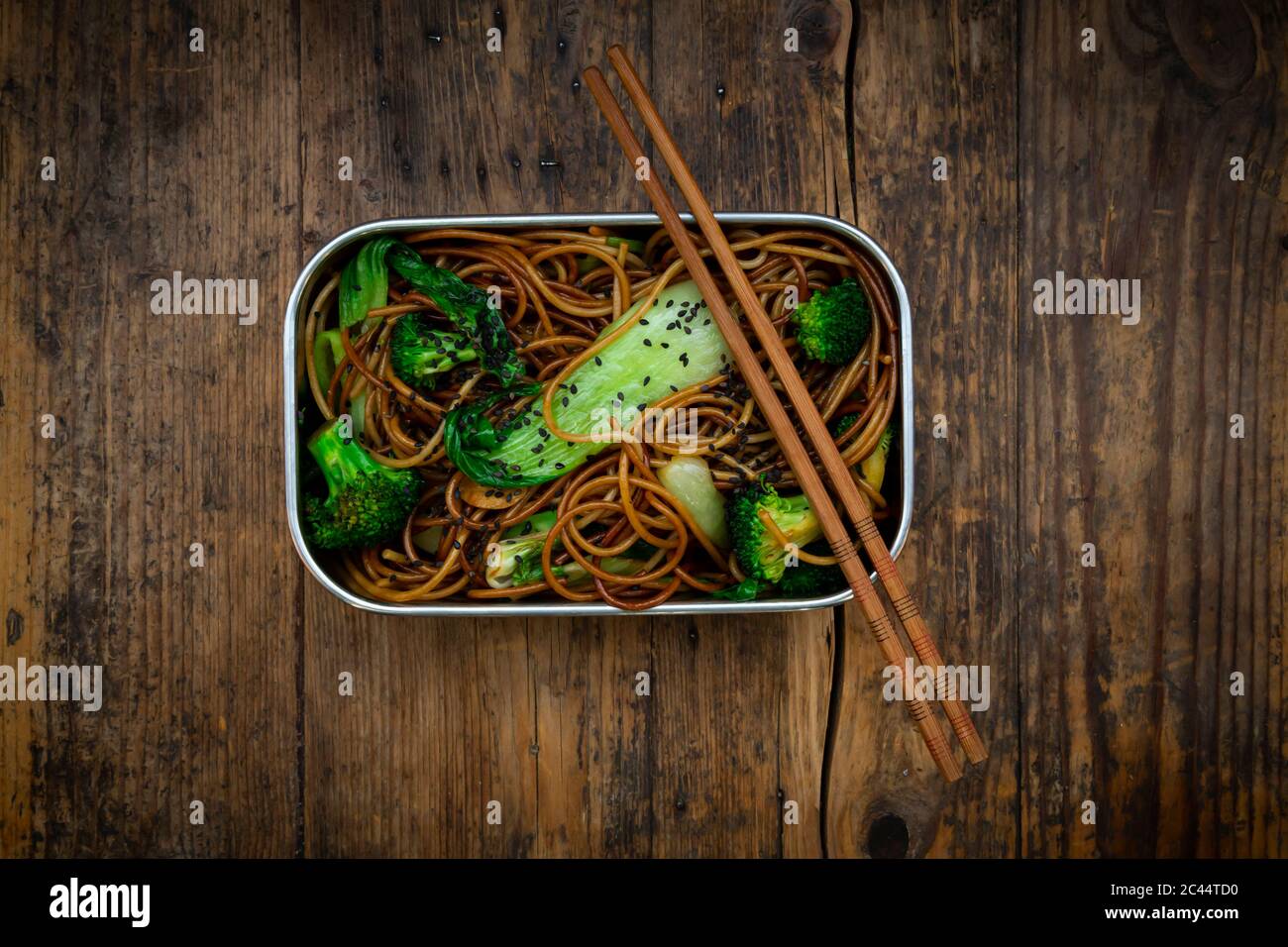 Lunch box of soba noodles with bok choy, broccoli, soy sauce and black