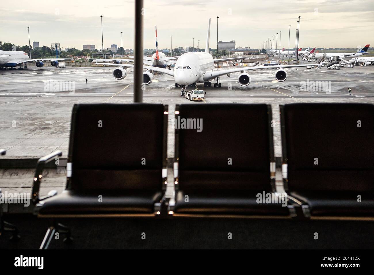 South Africa, Johannesburg, Airplane on tarmac seen from airport terminal with empty chairs in foreground Stock Photo