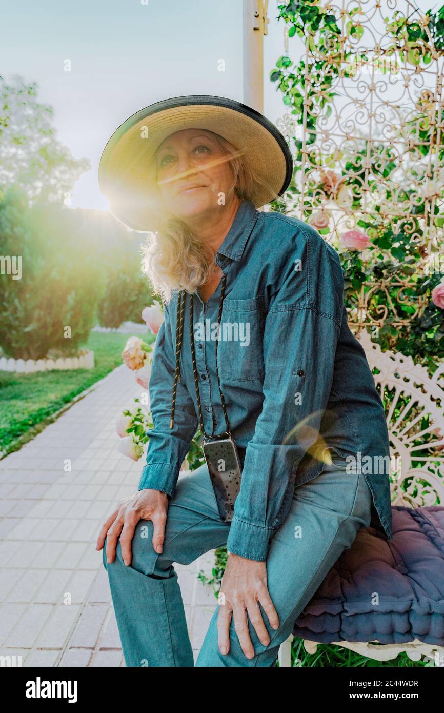 Portrait of smiling senior woman in her garden at backlight Stock Photo ...