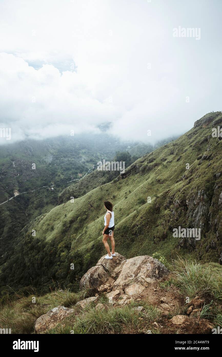 Sri Lanka, Uva Province, Ella, Female hiker standing on boulder at Little Adams Peak Stock Photo
