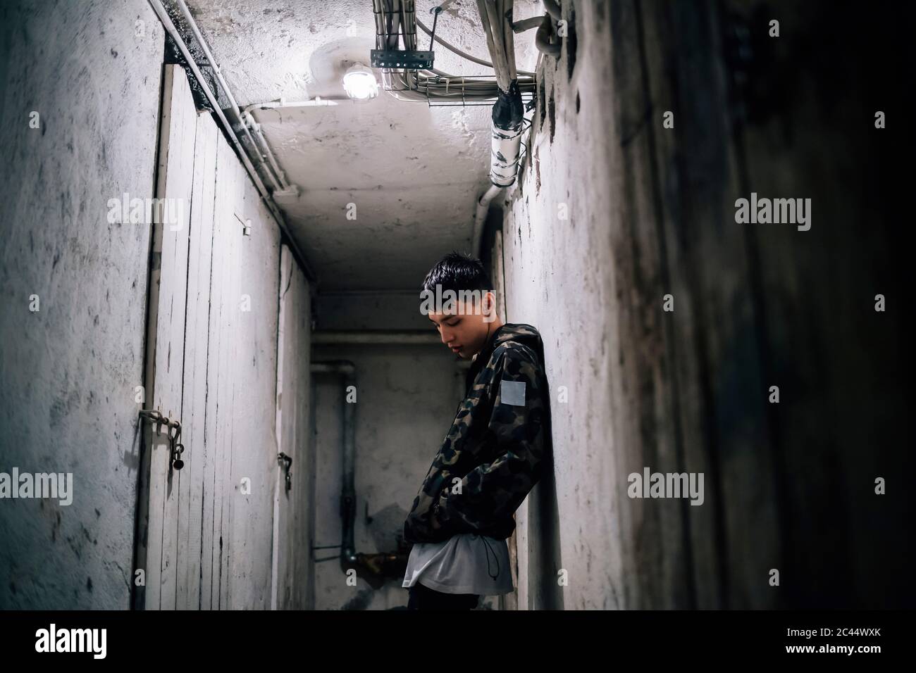 Thoughtful young man leaning on old wall Stock Photo