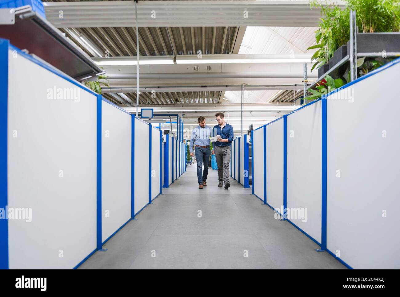 Two men with tablet walking and talking in factory Stock Photo - Alamy