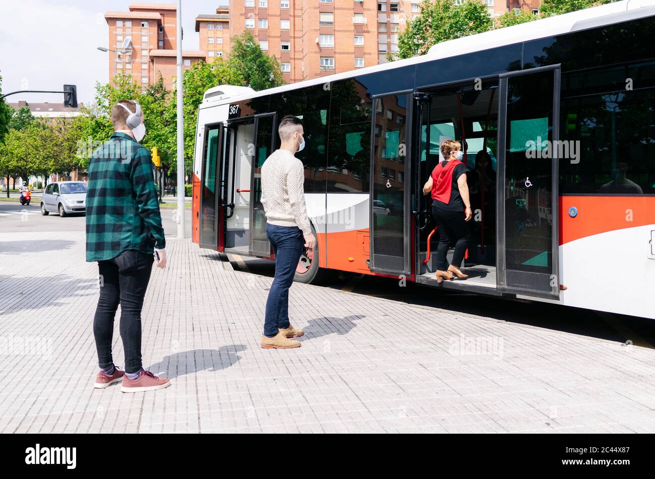 Passengers wearing protective masks getting into public bus hires