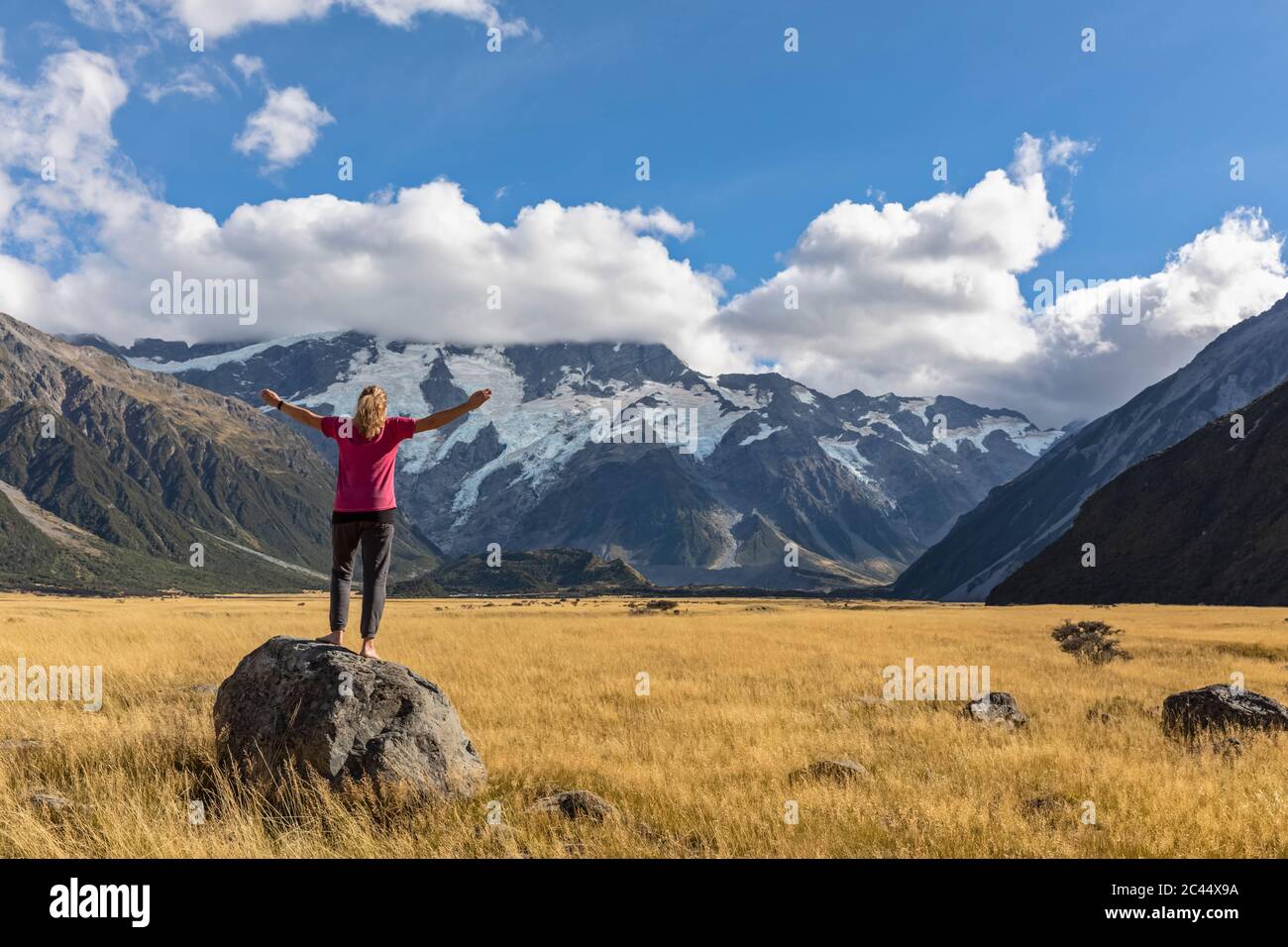 New Zealand, Oceania, South Island, Canterbury, Ben Ohau, Southern Alps (New Zealand Alps), Mount Cook National Park, Aoraki / Mount Cook, Woman standing on boulder in mountain landscape Stock Photo