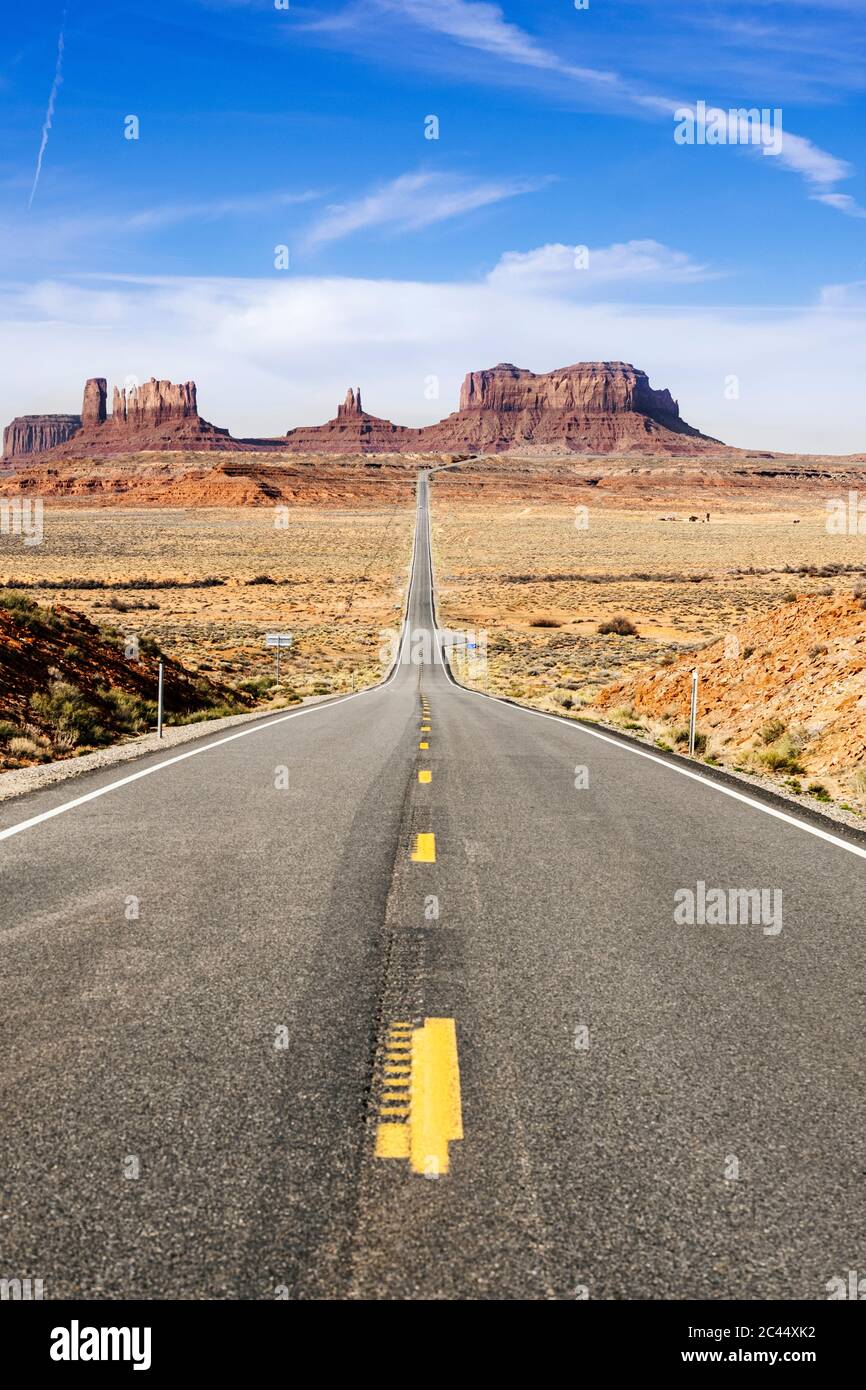 Empty desert road towards famous rock formation against sky, Monument Valley Tribal Park, Utah, USA Stock Photo