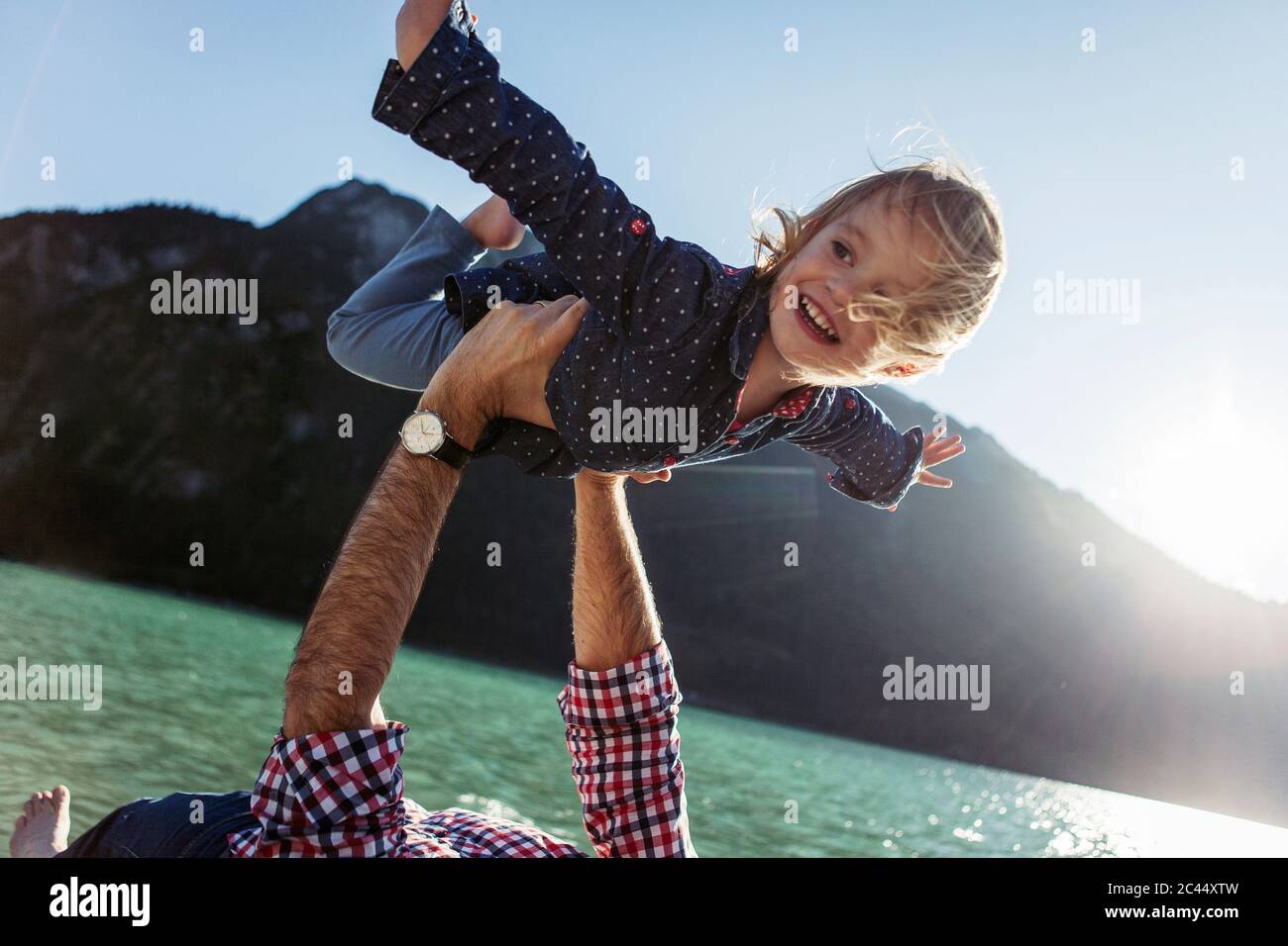 Happy girl with arms outstretched being carried by father at Achensee, Tyrol State, Austria Stock Photo