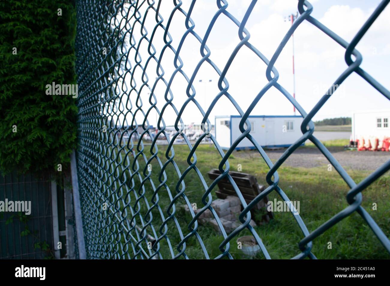 Closeup shot of a metal fence with a lawn and buildings on the ...