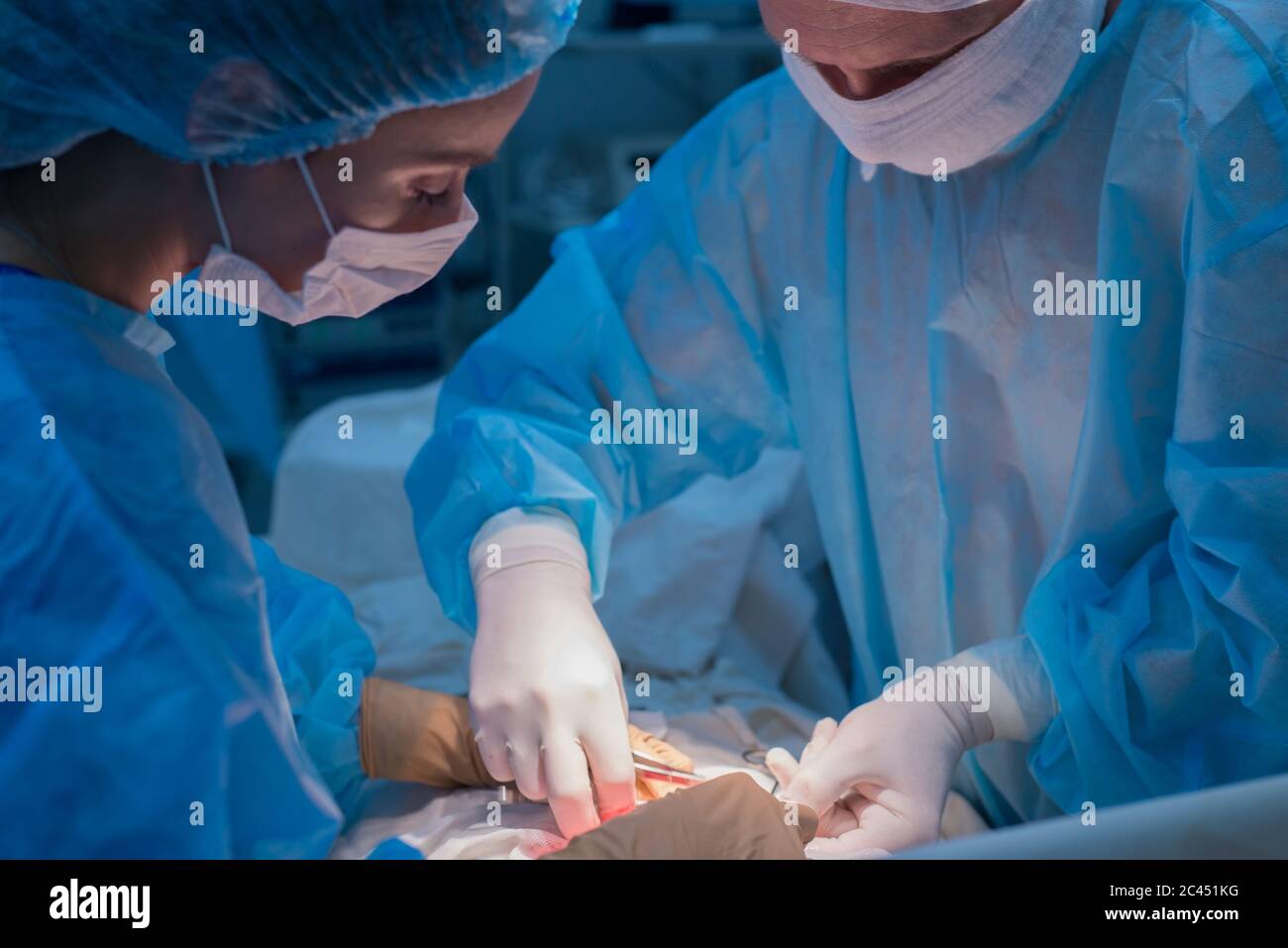 Children's surgeons perform urological surgery. A man and a woman in a mask, and a blue sterile gown, in the operating room. Stock Photo