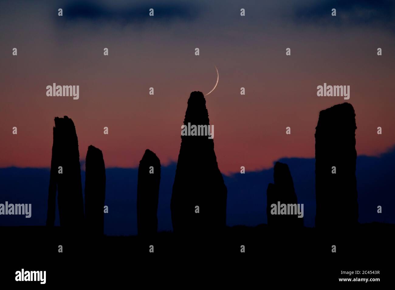 Crescent moon setting behind Ring of Brodgar, Orkney Isles Stock Photo