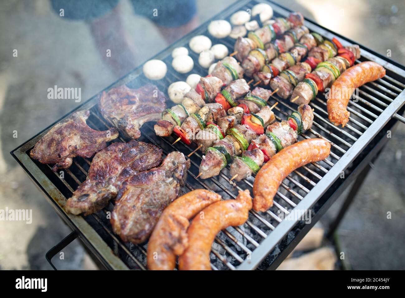 Selection of meat grilling over the coals on a portable barbecue Stock