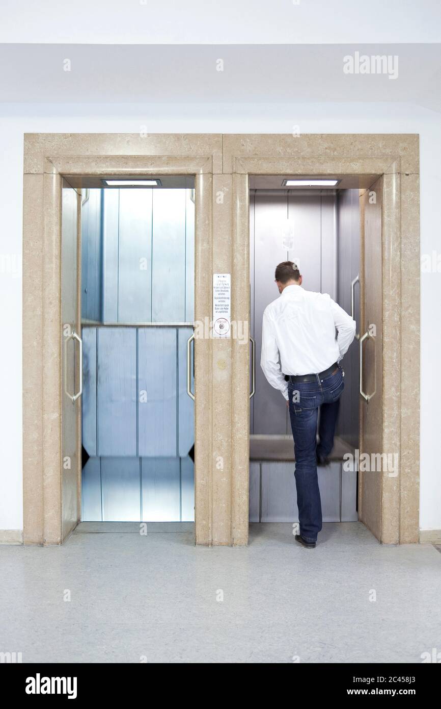 Man climbs into a paternoster lift Stock Photo