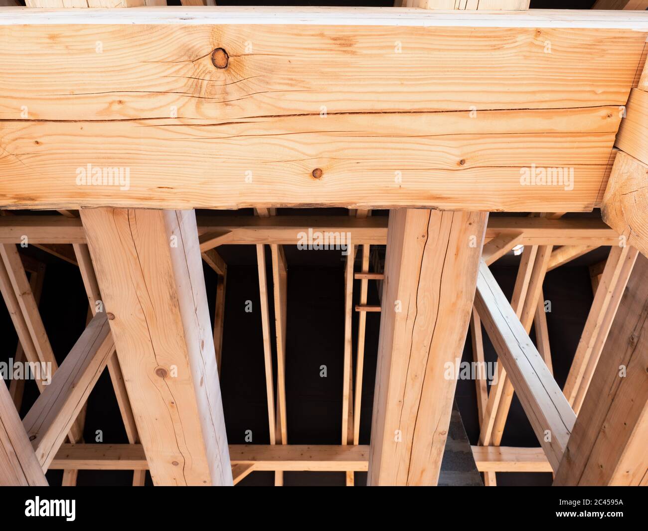 Roofing construction with wooden beams, low angle view. Big spruce logs ...