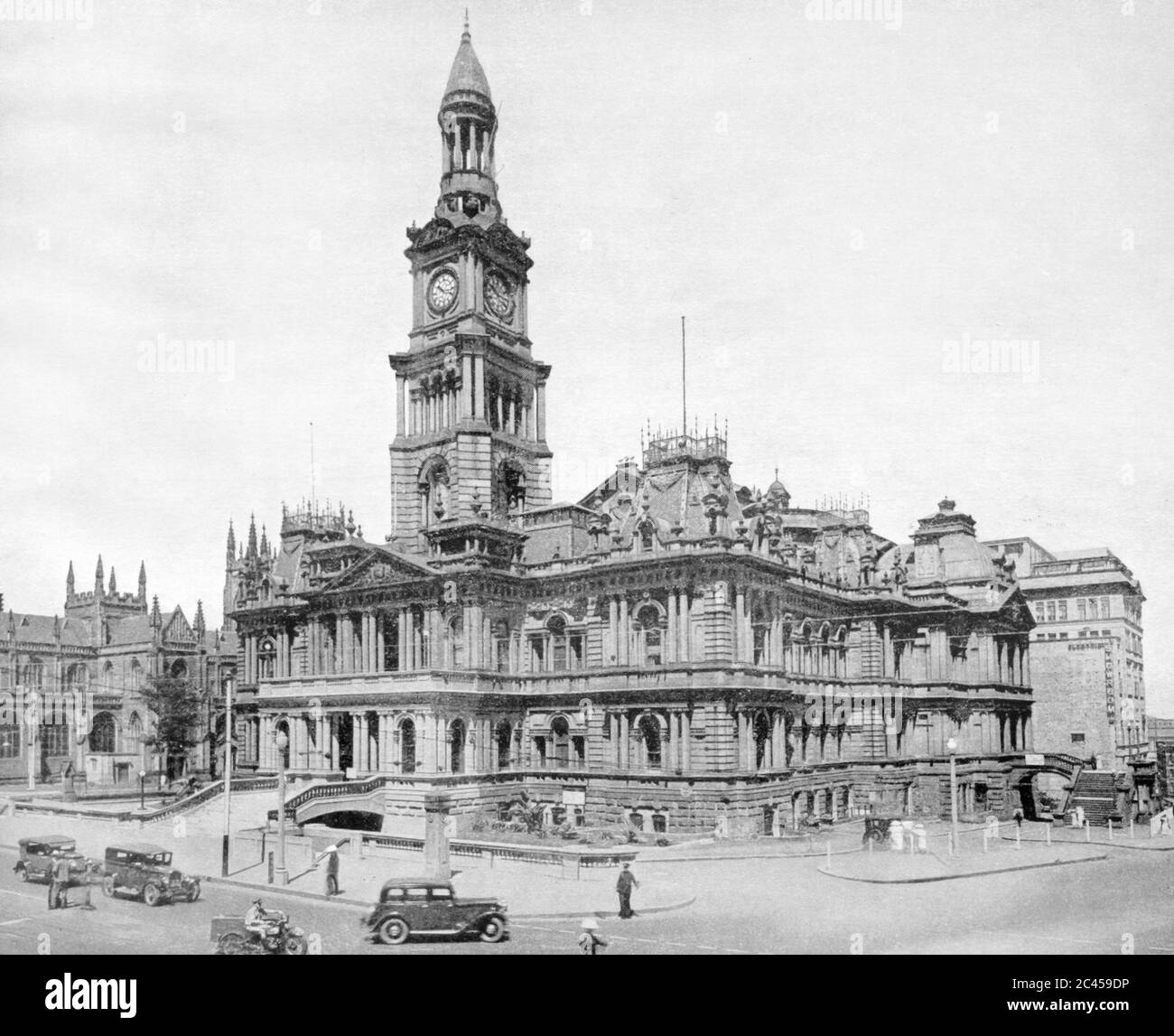 Sydney Australia 1938: The Sydney Town Hall in pre war Sydney with St Andrews Cathedral to its left. Curiously in the lower left corner two men appear to be having a close up (possibly heated) conversation of sorts. This image was published in a 1938 book by Municipal Council of Sydney to commemorate 'the 150th anniversary of the founding of a nation' Stock Photo