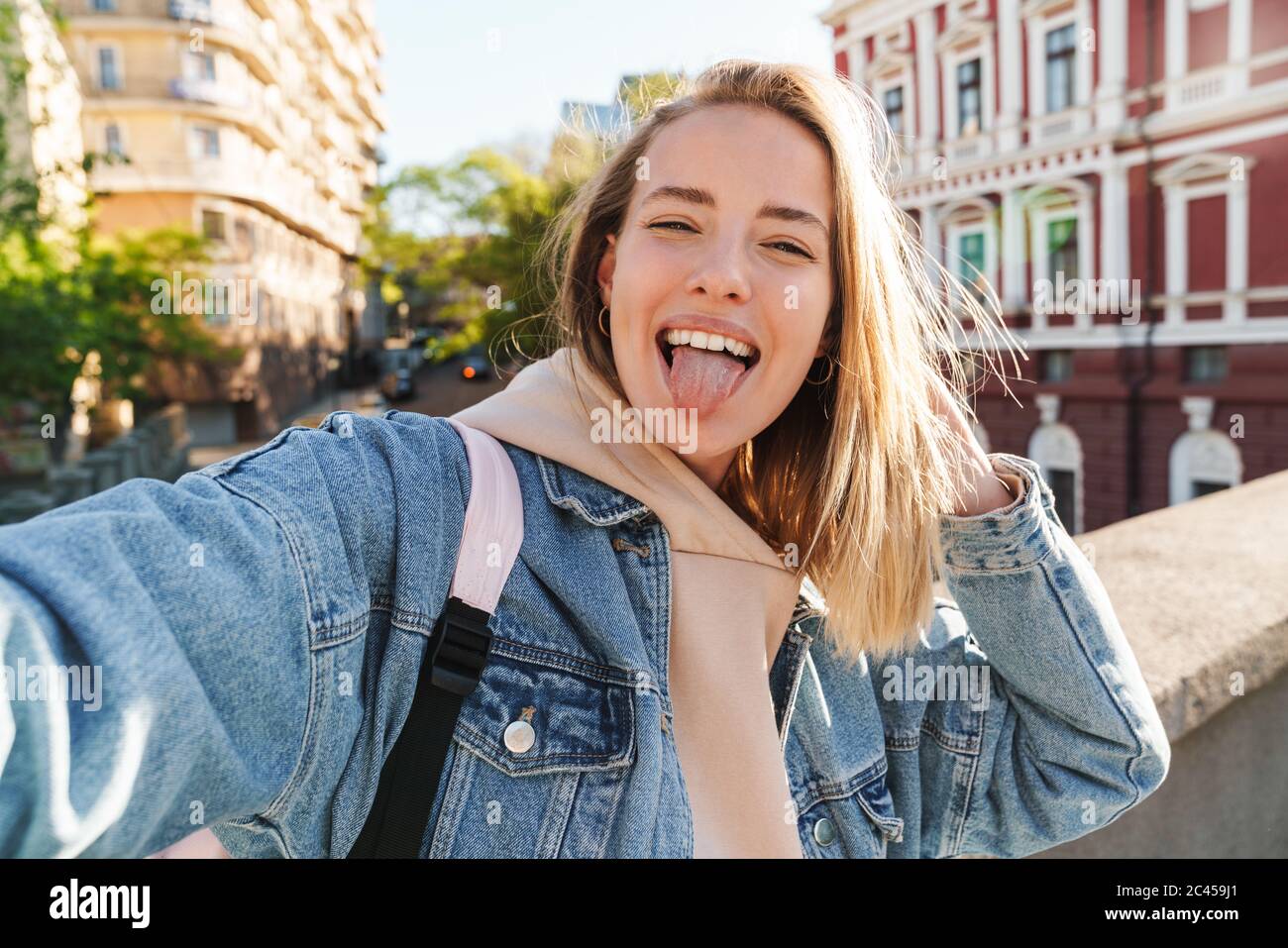 Beautiful cheerful young blonde woman wearing denim jacket walking in ...