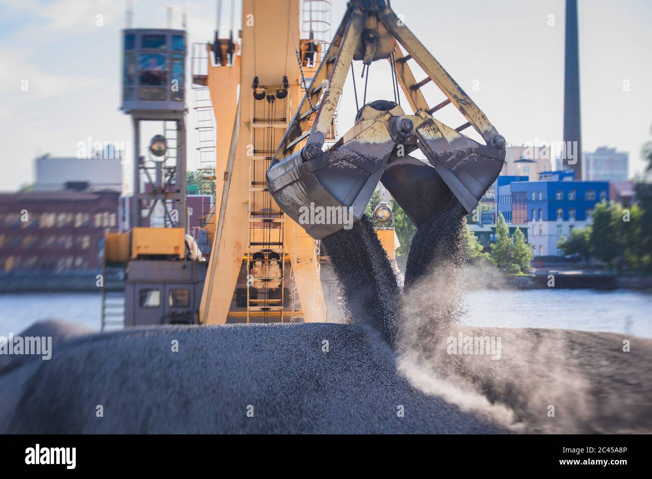 Bulk-handling crane unloading sand, road metal and gravel from cargo vessel ship, heavy vehicle and portal crane loader working with bulk materials in Stock Photo