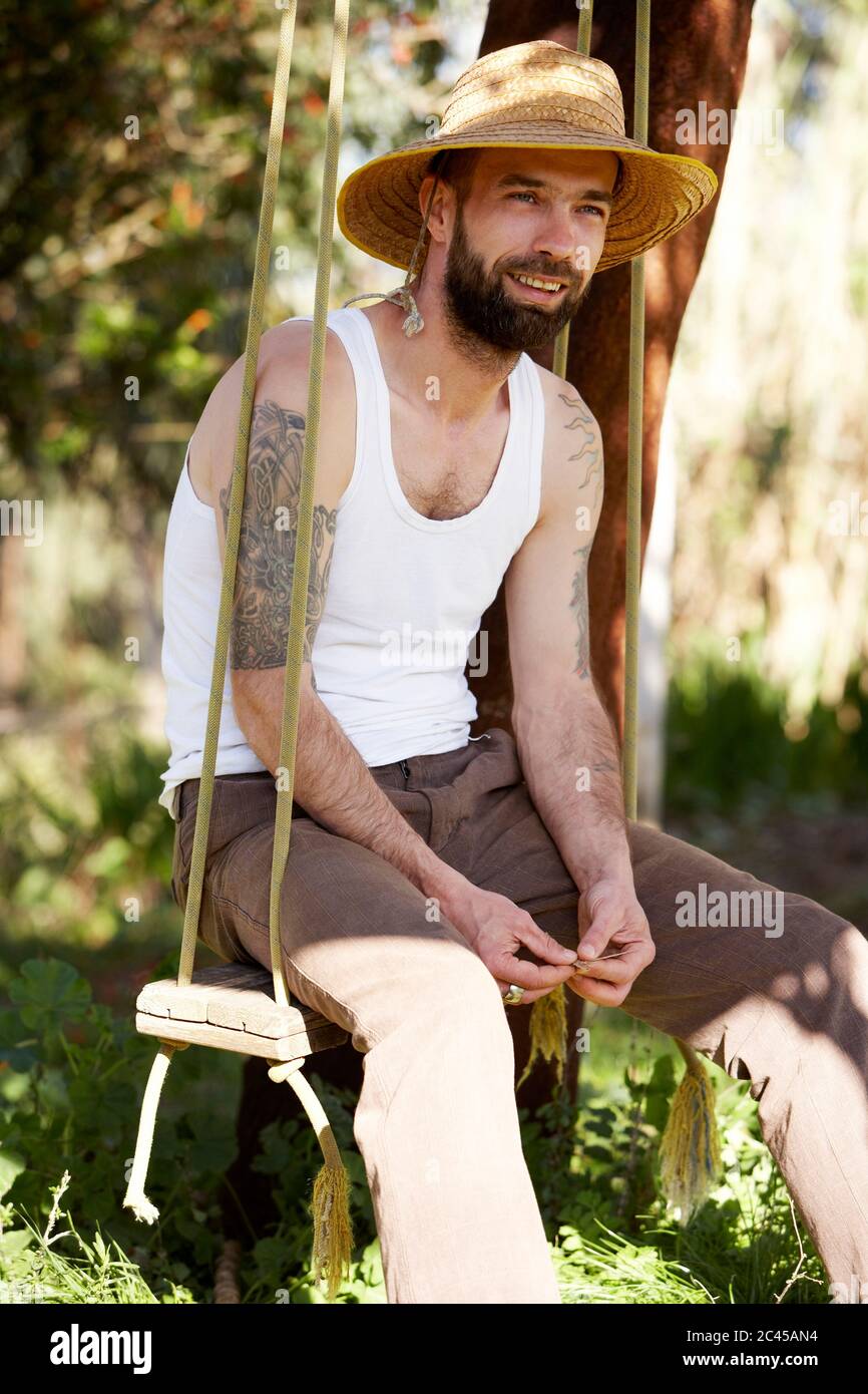 Man in a straw hat sits on a swing Stock Photo
