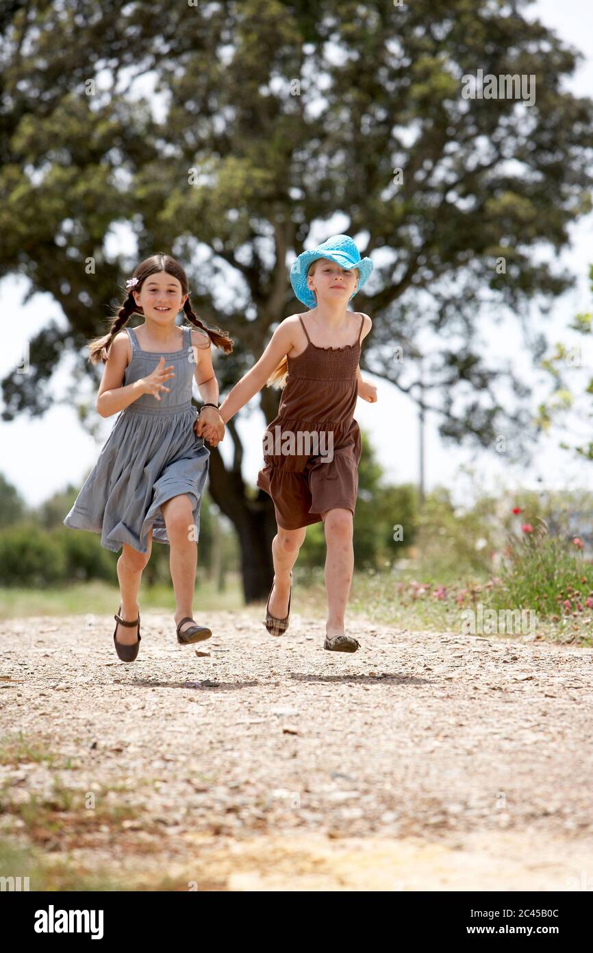 Two girls walk hand in hand on a path Stock Photo