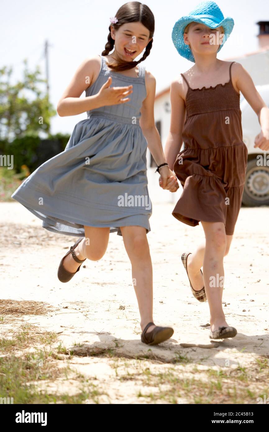 Two girls walk hand in hand on a path Stock Photo - Alamy