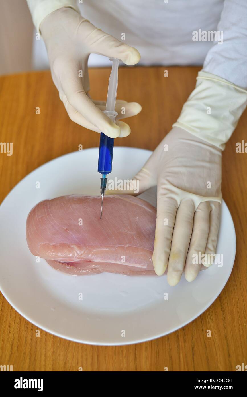Food scientist injecting raw chicken Stock Photo