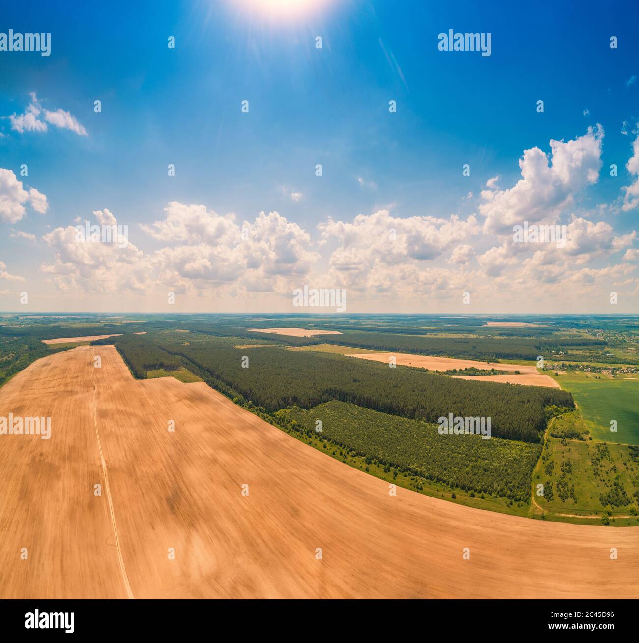 Rural landscape with a beautiful sky, aerial view. Skyview of the countryside. View of plowed and green fields and pine forest in spring Stock Photo