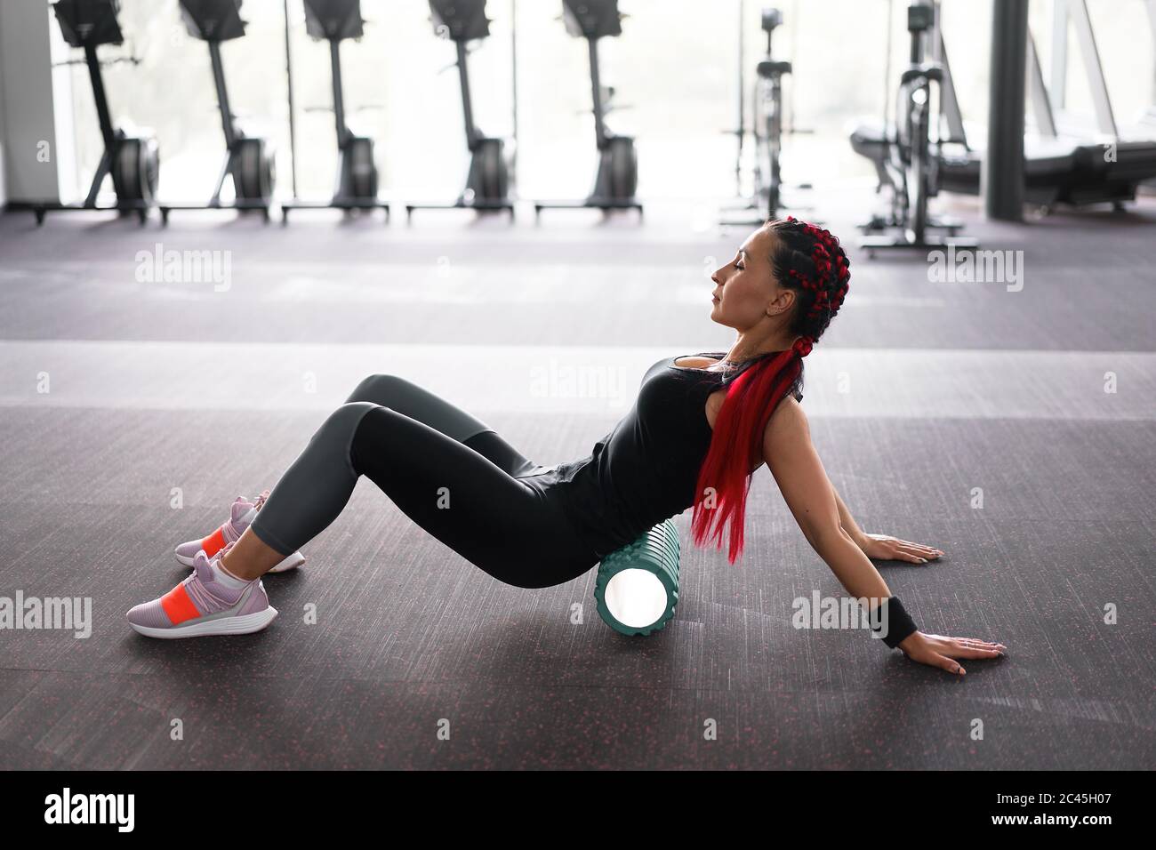 Woman massaging foam roll leg gym myofascial release exercise rolling