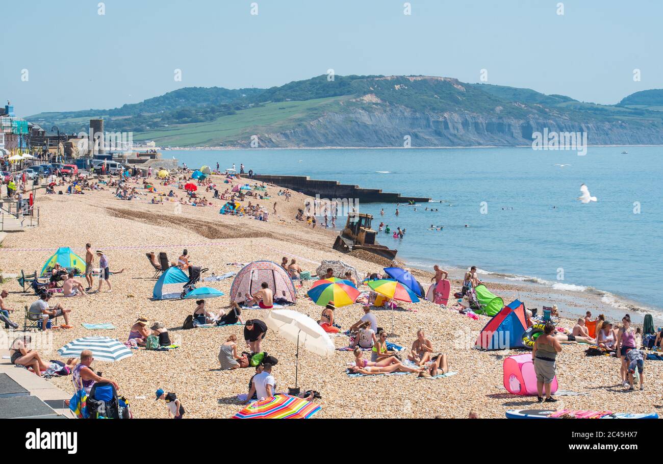 Lyme Regis, Dorset, UK. 24th June, 2020. UK Weather. Beachgoers flock to the seaside resort of Lyme Regis to soak up the scorching hot sunshine on the hottest day of the year only to find the town's main beach closed for major dredging works. Businesses in the town, already suffering major losses from the coronavirus lockdown, could be forgiven for questionning the timing of the works which are taking place on a glorious sunny day just as the town is beignning to welcome visitors back Credit: Celia McMahon/Alamy Live News Stock Photo