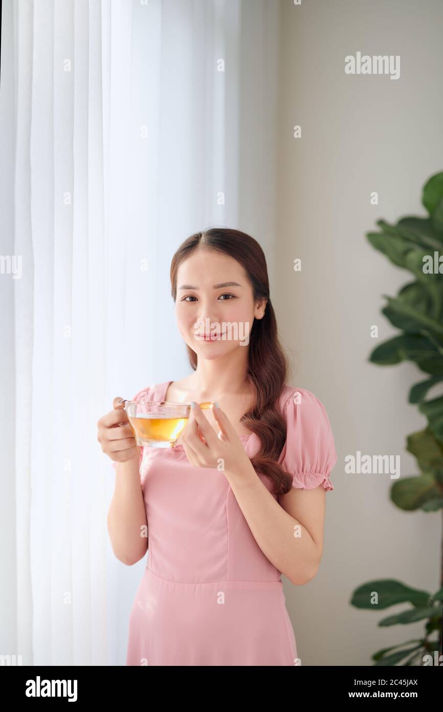 Young woman with glass of water taking vitamin pill at home Stock Photo