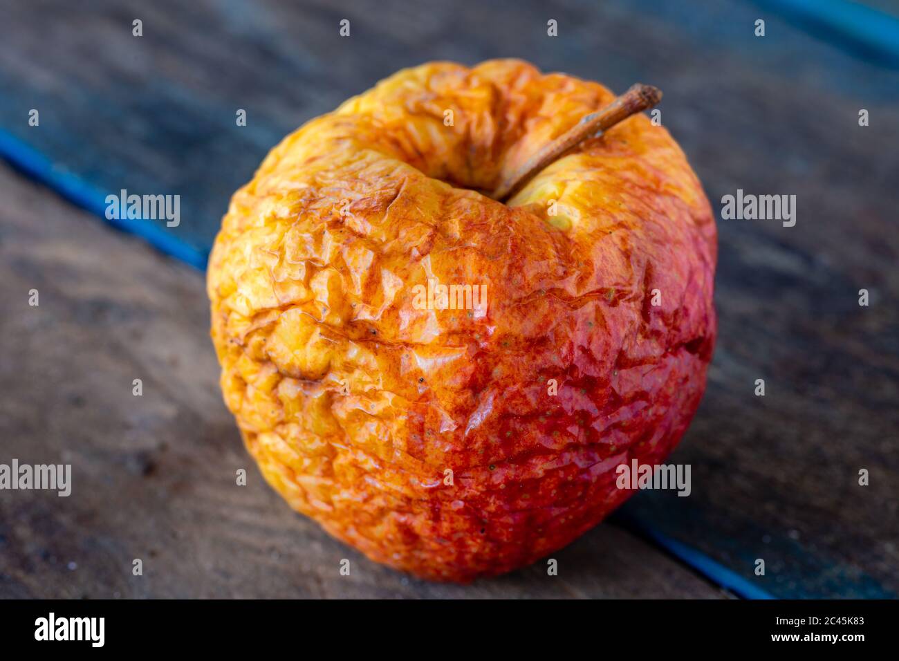 Rotten apple. Spoiled food. Food waste. Apple on old boards. Stock Photo