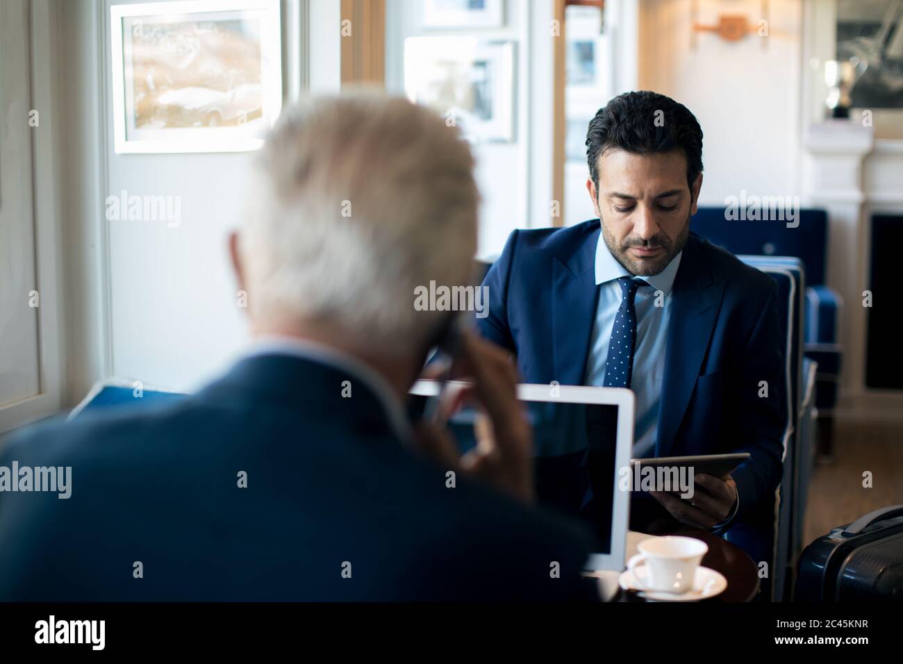 Two businessmen sitting indoors, talking. Stock Photo