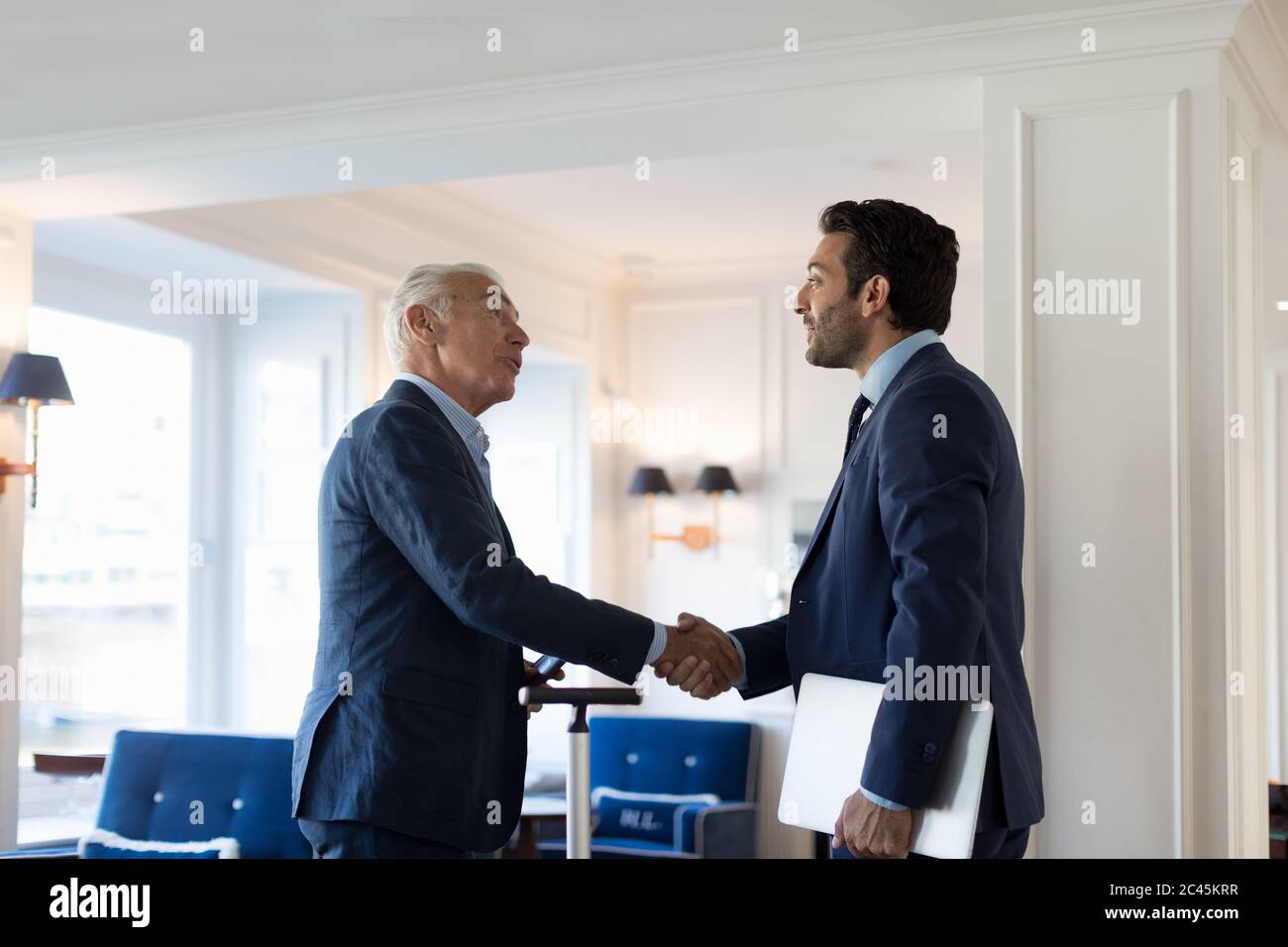 Two businessmen standing indoors, shaking hands. Stock Photo