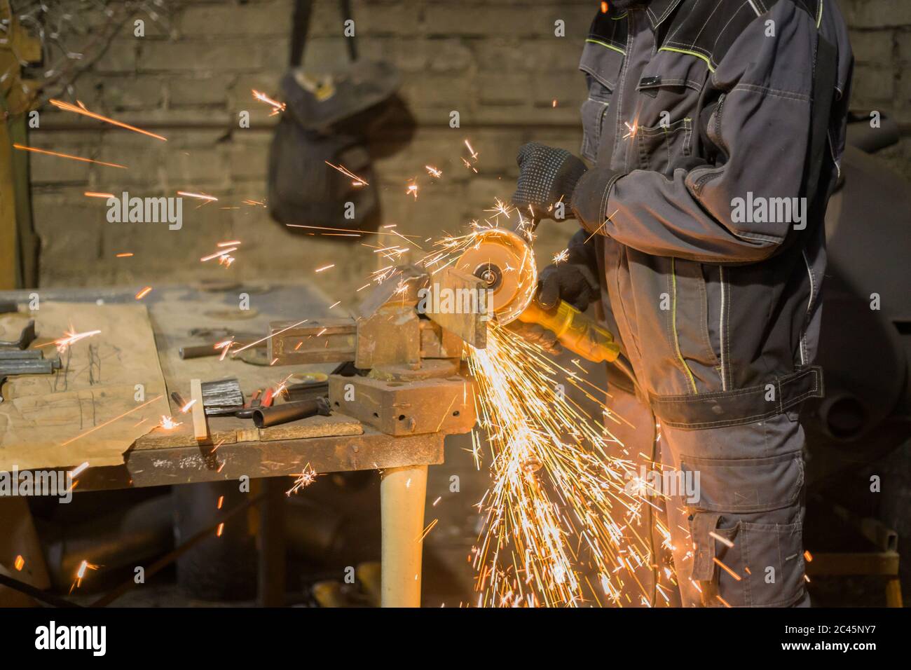 Professional blacksmith sawing metal with hand circular saw at forge ...