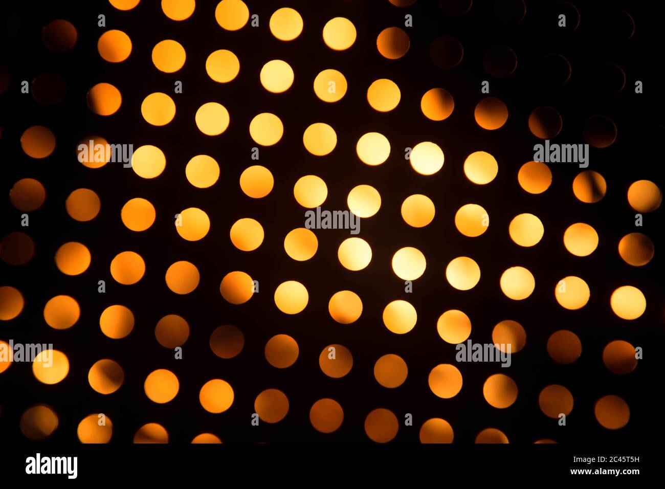 Metal surface with holes on a blurred orange background Stock Photo