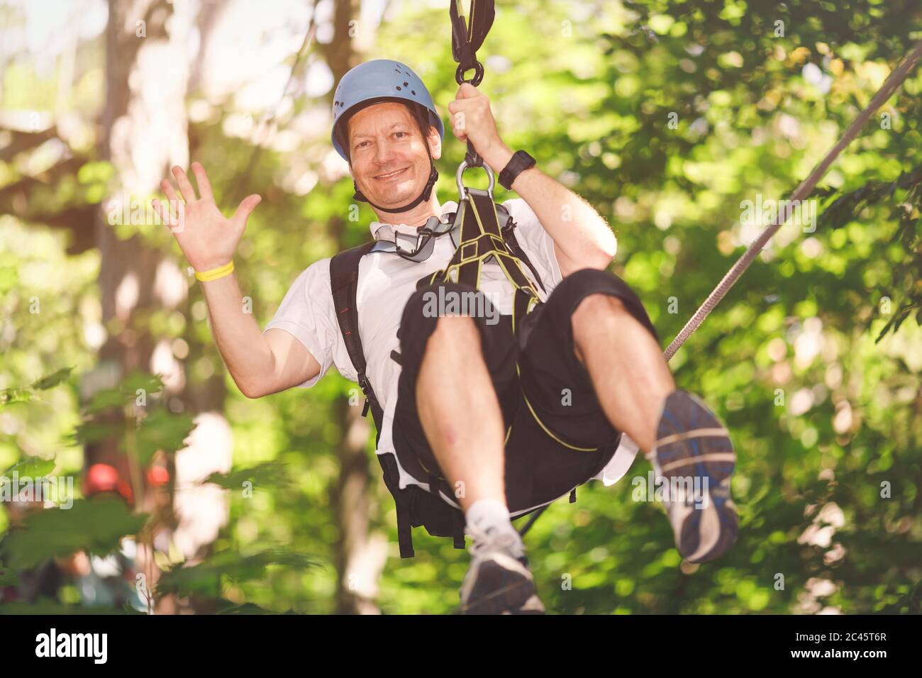 Middle aged man going by flying fox in forest rope park Stock Photo